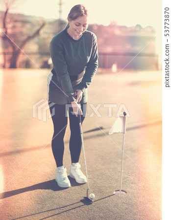 Female golf player getting ready to hit ball Female golf player getting ready to hit ball 53773870