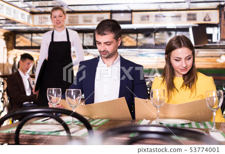 Couple with menu is choosing order in time dinner 53774001