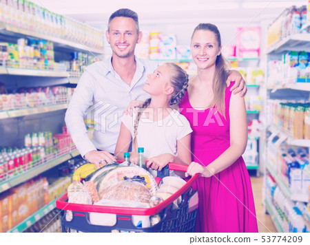 Portrait of customers which is standing with full trolley of goods Portrait of customers which is standing with full trolley of goods 53774209