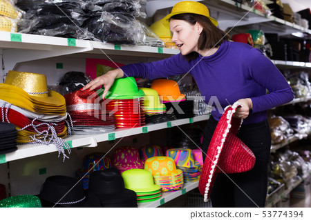 Girl choosing party hats on shelves in shop 53774394