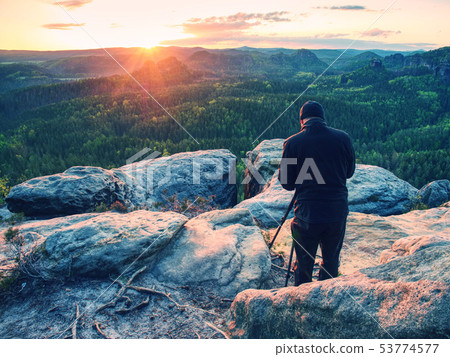 Photographer with tripod on cliff and thinking. 53774577