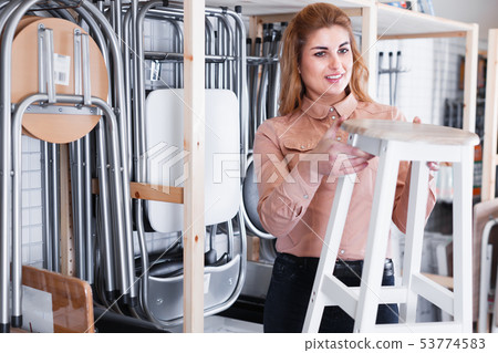 Young woman looking for new stylish tabouret Young woman looking for new stylish tabouret 53774583