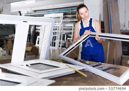 Young smiling woman worker with plastic window frame Young smiling woman worker with plastic window frame 53774694