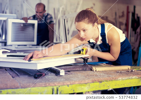 Workwoman controlling size of finished PVC window Workwoman controlling size of finished PVC window 53774832