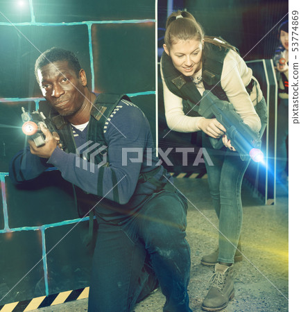 Young man and woman playing laser tag Young man and woman playing laser tag 53774869