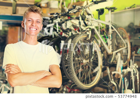 Portrait of male standing near the bicycle in the shop Portrait of male standing near the bicycle in the shop 53774948