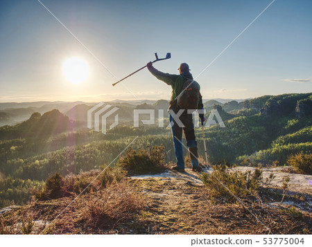 Hiker with medicine crutch achieved mountain peak. 53775004