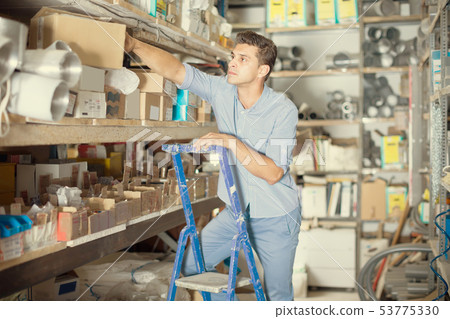 foreman is standing on the stairs near the shelves with boxes foreman is standing on the stairs near the shelves with boxes 53775330