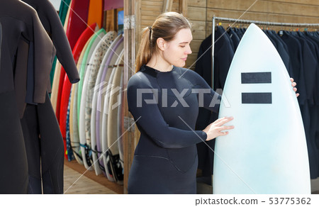 female wearing surf suit with surfboard 53775362