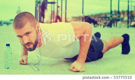 man performs push-ups on sportsground man performs push-ups on sportsground 53775510