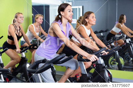 Girls during workout on stationary bicycle in fitness gym 53775607