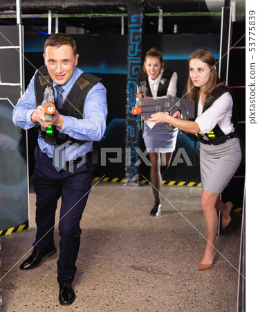 Group of colleagues holding laser pistols playing laser tag game Group of colleagues holding laser pistols playing laser tag game 53775839
