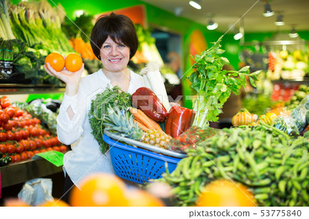 Middle aged woman with basket choosing fruits Middle aged woman with basket choosing fruits 53775840