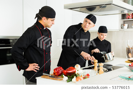 Professional chefs in black uniform working with vegetables Professional chefs in black uniform working with vegetables 53776015