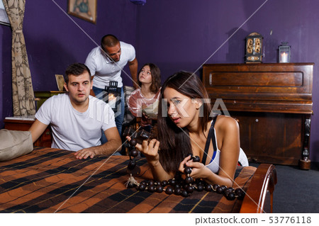 Young adults inspecting wooden rosary in escape room Young adults inspecting wooden rosary in escape room 53776118