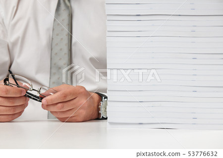 Businessman working at an office, reads stack of Businessman working at an office, reads stack of 53776632