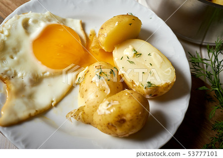 close up on fried eggs with young potatoes with butter and dill 53777101