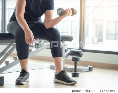 Plump woman start working out with dumbbell weight 53778365