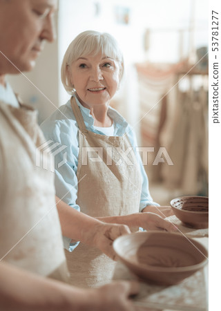 Waist up of female potter looking at clay master in workshop 53781277
