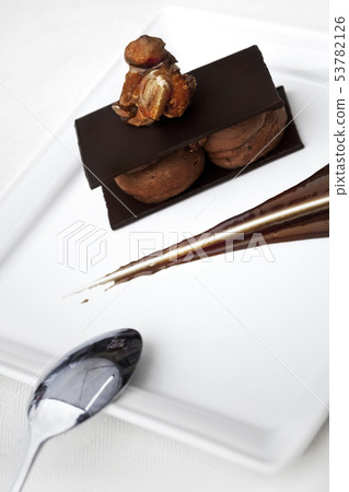 Chocolate dessert and spoon on a white plate 53782126