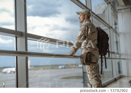 Side view of American soldier in camouflage looking at window Side view of American soldier in camouflage looking at window 53782902