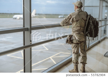 Full length of American soldier in camouflage looking at the window Full length of American soldier in camouflage looking at the window 53782904