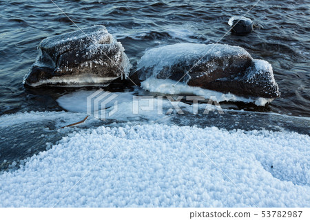 Ice frozen over rocks in lake shore Ice frozen over rocks in lake shore 53782987