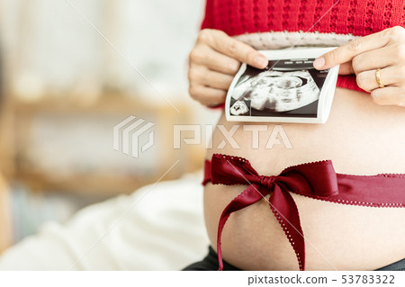 Close up of pregnant woman holding ultrasound scan Close up of pregnant woman holding ultrasound scan 53783322