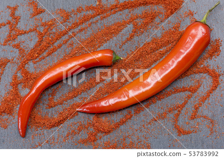 Raw red chili peppers and ground paprika on stone Raw red chili peppers and ground paprika on stone 53783992