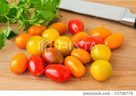 Multicolored cherry tomatoes heap, parsley, knife 53786779