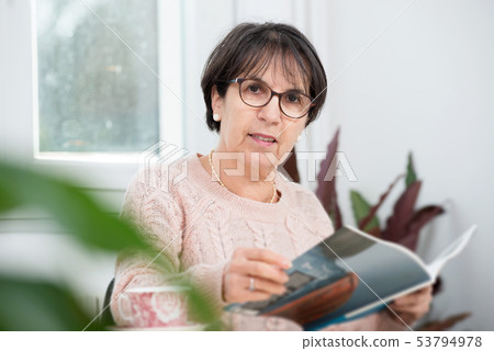 mature brunette woman reading magazine 53794978