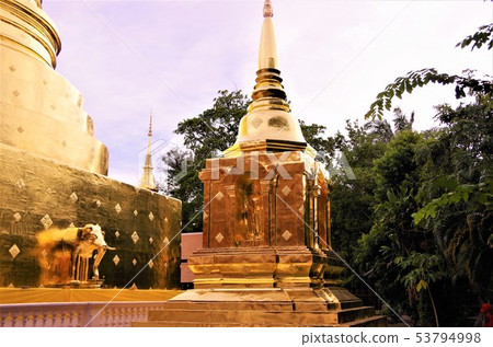 Pagodas and images of Thai Buddhist temples that glow golden at dusk (Thailand) 53794998