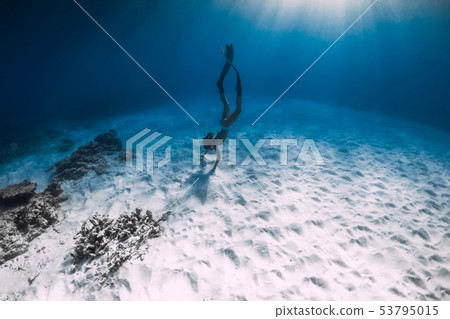 Young woman freediver glides over sandy sea bottom Young woman freediver glides over sandy sea bottom 53795015