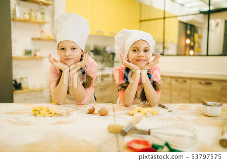 Little girls cooks in caps sitting at the table 53797575
