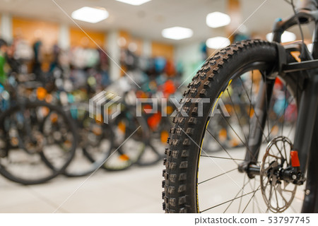 Bicycle in sports shop, focus on front wheel Bicycle in sports shop, focus on front wheel 53797745