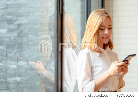 Young businesswoman standing with mobile phone Young businesswoman standing with mobile phone 53799166