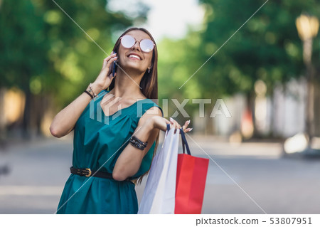Close up of young charming dark-haired caucasian female with shopping bags smiling with teeth and Close up of young charming dark-haired caucasian female with shopping bags smiling with teeth and 53807951