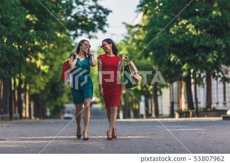 Beautiful girls with shopping bags walking at the summer city street. Shopping day concept. Beautiful girls with shopping bags walking at the summer city street. Shopping day concept. 53807962