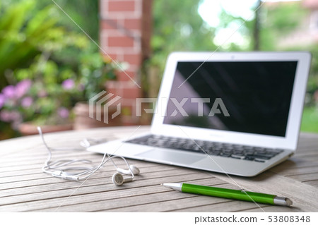 Laptop with ear phones, garden background Laptop with ear phones, garden background 53808348