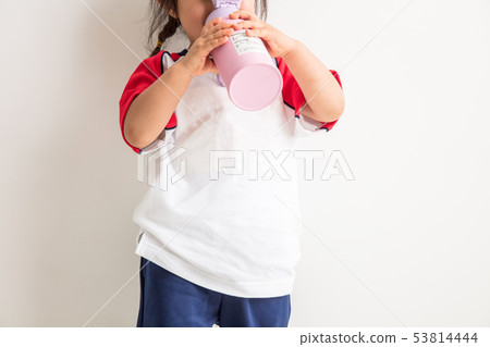 A sporting event in which a kids girl in an exercise clothes on a white background is drinking with a water bottle A sporting event in which a kids girl in an exercise clothes on a white background is drinking with a water bottle 53814444