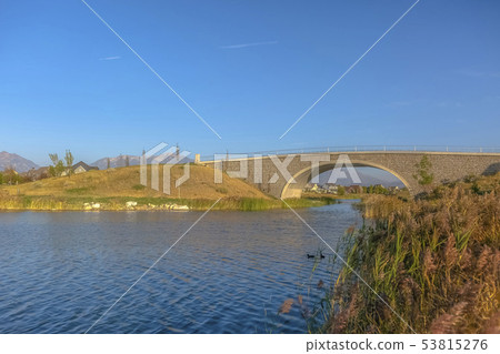 Arched bridge and Oquirrh Lake against blue sky 53815276