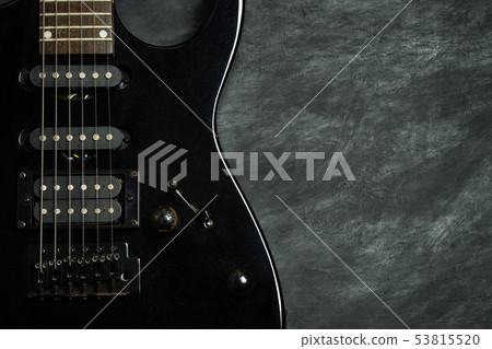 Black electric guitar on black cement floor. 53815520