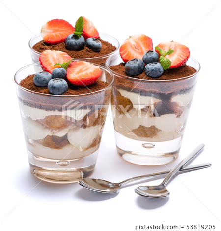 Classic tiramisu dessert with blueberries and strawberries in a glass isolated on a white background Classic tiramisu dessert with blueberries and strawberries in a glass isolated on a white background 53819205