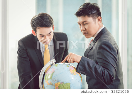 Two businessmen looking at globe 53821036