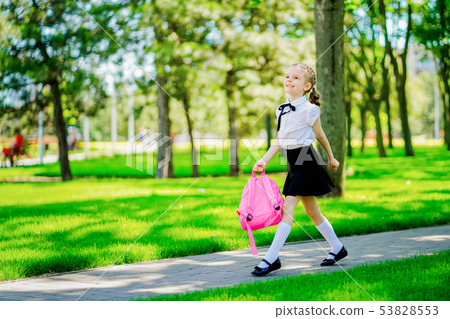 Portrait of happy Caucasian young smiling girl wearing school backpack outside the primary school 53828553