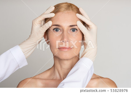 Cosmetic Surgery Concept. Doctor Examining Mature Woman Face Cosmetic Surgery Concept. Doctor Examining Mature Woman Face 53828976