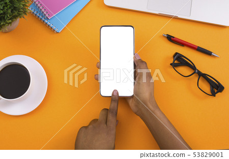 Woman using blank smartphone on orange background Woman using blank smartphone on orange background 53829001
