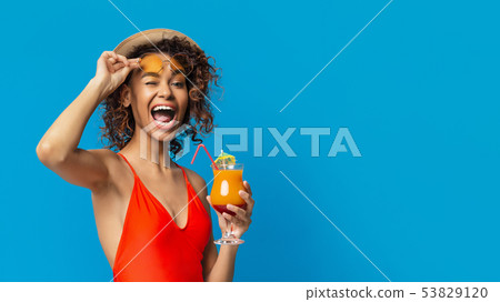 Cute black girl enjoying cocktail and winking to camera 53829120