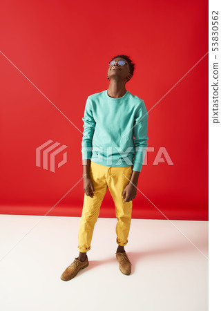 Young Afro American guy in glasses posing on red background Young Afro American guy in glasses posing on red background 53830562