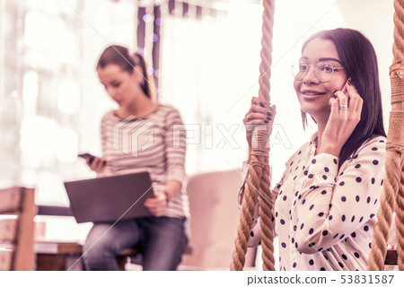 Dark-eyed appealing woman holding her smartphone while calling her boyfriend Dark-eyed appealing woman holding her smartphone while calling her boyfriend 53831587